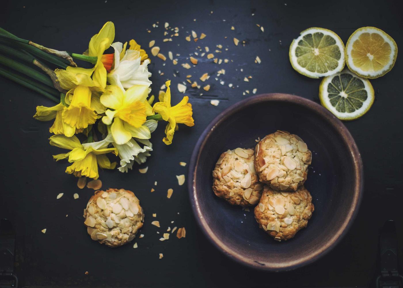 Oat cookies on a dark plate with lemon slices and yellow flowers