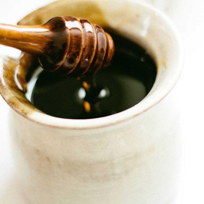Honey dripping from a wooden dipper into a cup