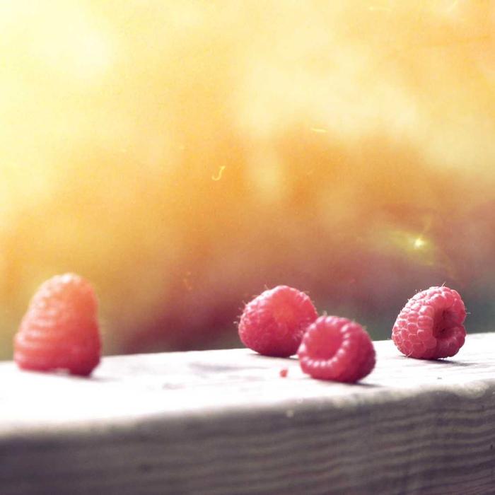 Three raspberries on a sunlit table
