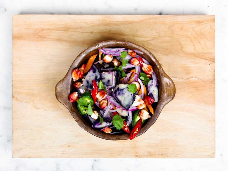 Bowl of charred peppers, onions and greens on a wooden board