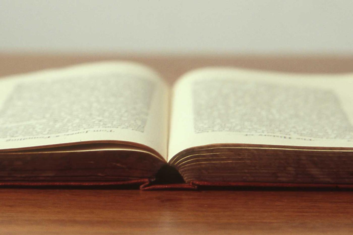 An open book resting on a wooden desk