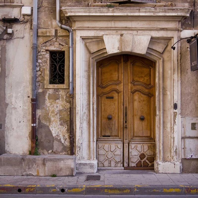 A weathered carved wooden double door set in an old stone wall