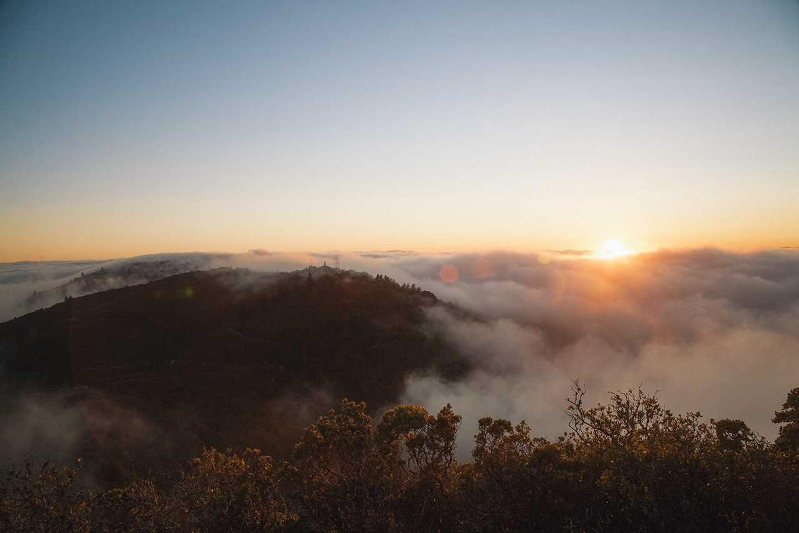 The sun setting over misty hills, seen from high up