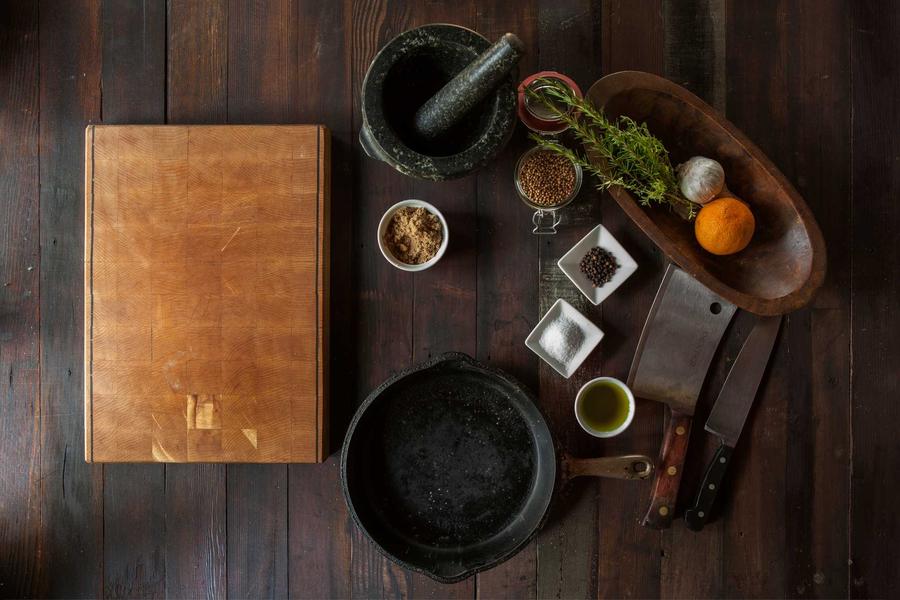 Whole spices, a mortar and pestle and small bowls on a dark wooden counter