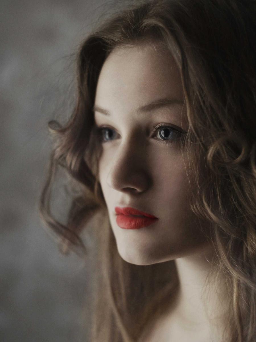 Close-up portrait of a woman with soft, wavy shoulder-length hair and red lipstick