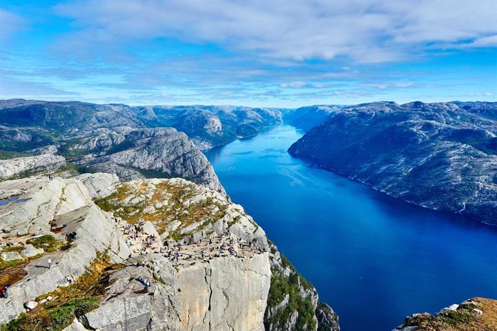 A deep blue fjord between granite cliffs, seen from the cliff edge