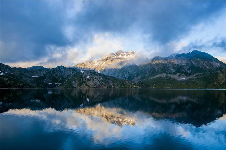 Mountains and clouds mirrored perfectly in a still lake