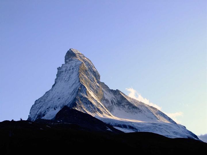 A lone pyramidal snow peak against a clear lavender sky